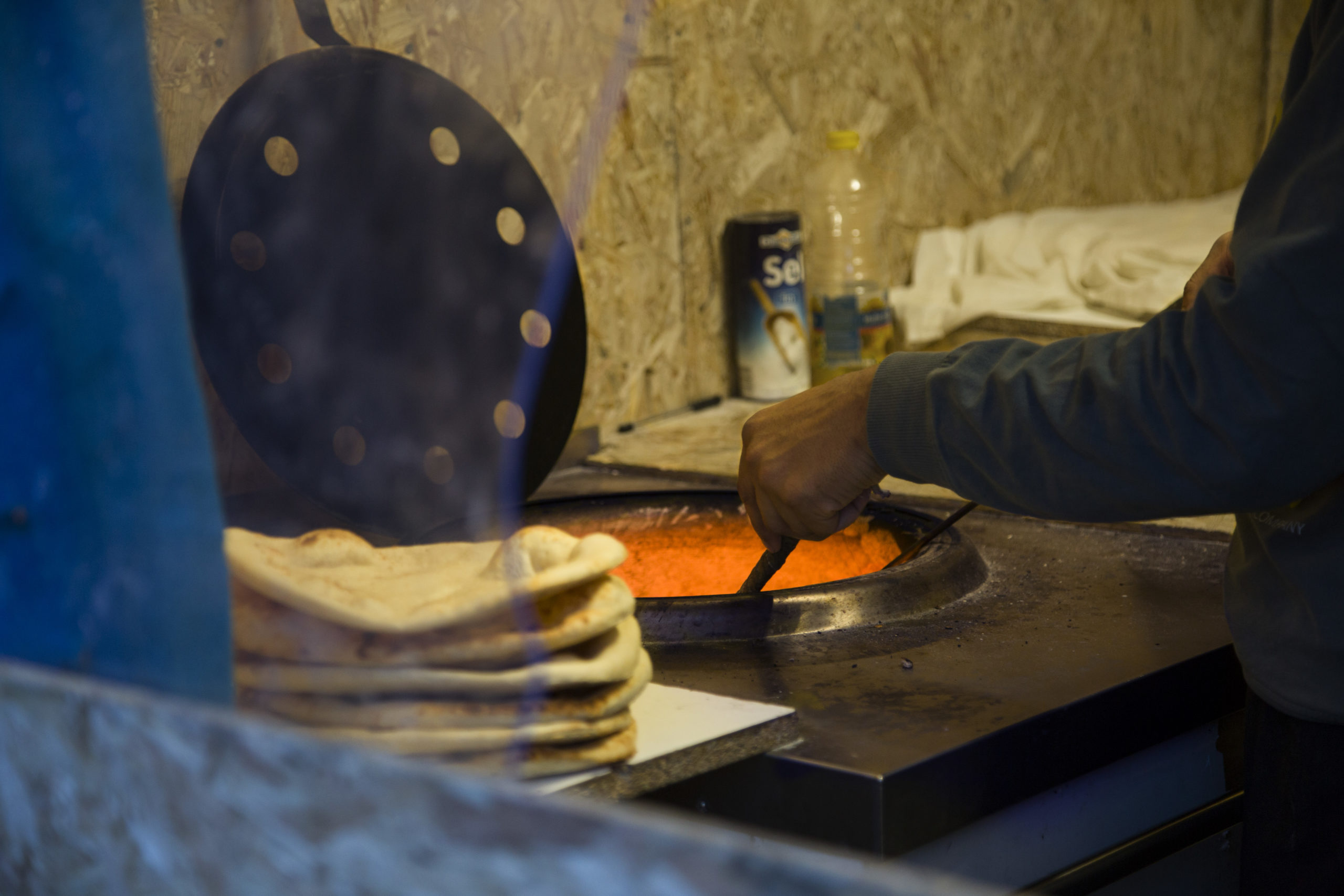 Des galettes de pain cuisent sur les parois du four.